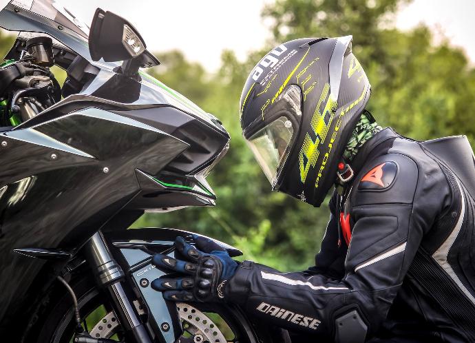 Rider person wearing helmet while holding motorcycle