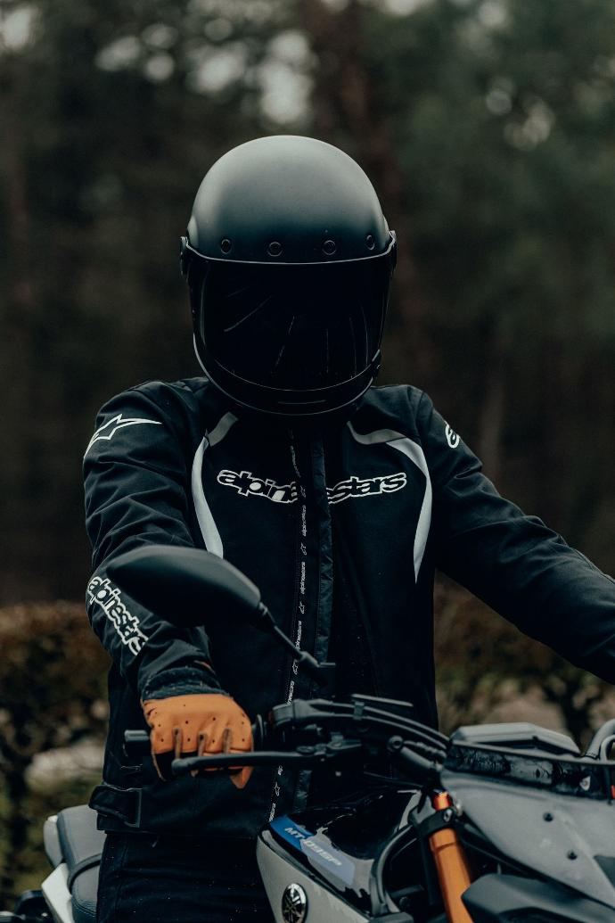 Rider man in black and orange helmet riding black motorcycle